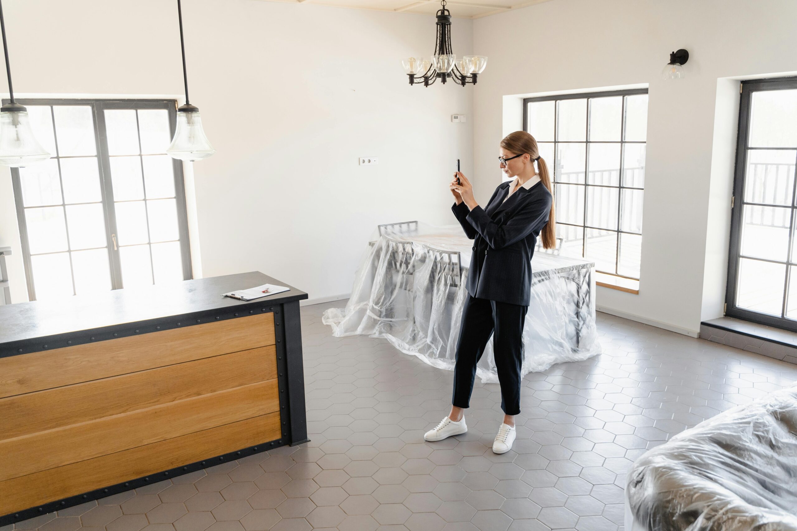 A real estate agent taking pictures of a modern, empty house interior.
